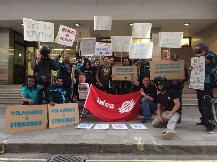 Striking Deliveroo workers holding banners with IWWGB in centre